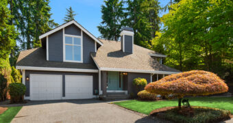Driveway and two car garage of Highland Pointe Kirkland home with lawn and sculpted ornamental tree