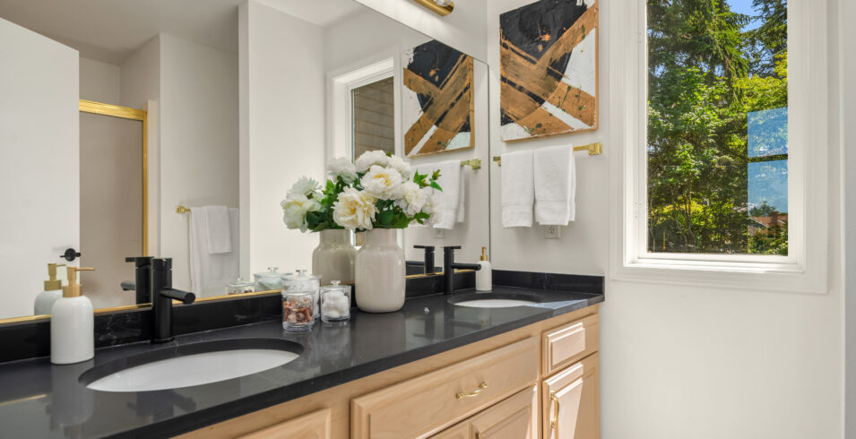 Bathroom vanity with black countertop, updated black fixtures, and natural light in Kirkland Highlands home