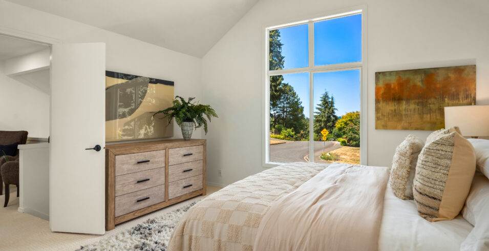 Primary bedroom with dresser, vaulted ceiling, and bright window in Kirkland Highlands home for sale
