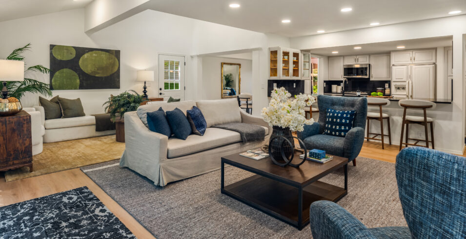 Family room with blue armchairs open to white kitchen with breakfast bar in Kirkland Highlands home