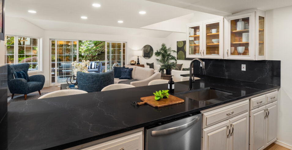 Kitchen with black quartz peninsula, full slab backsplash, and glass front cabinets in Kirkland Highlands home