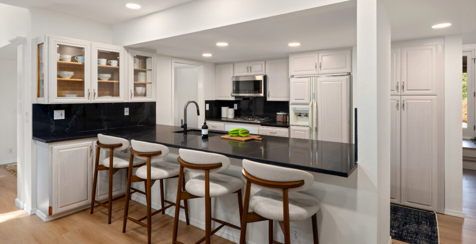 Kitchen breakfast bar with stool seating and black quartz counters in Kirkland Highlands home