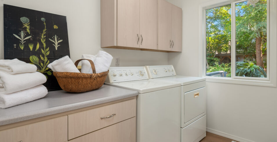 Laundry room with washer, dryer, folding counter, cabinets, and window in Kirkland Highlands home